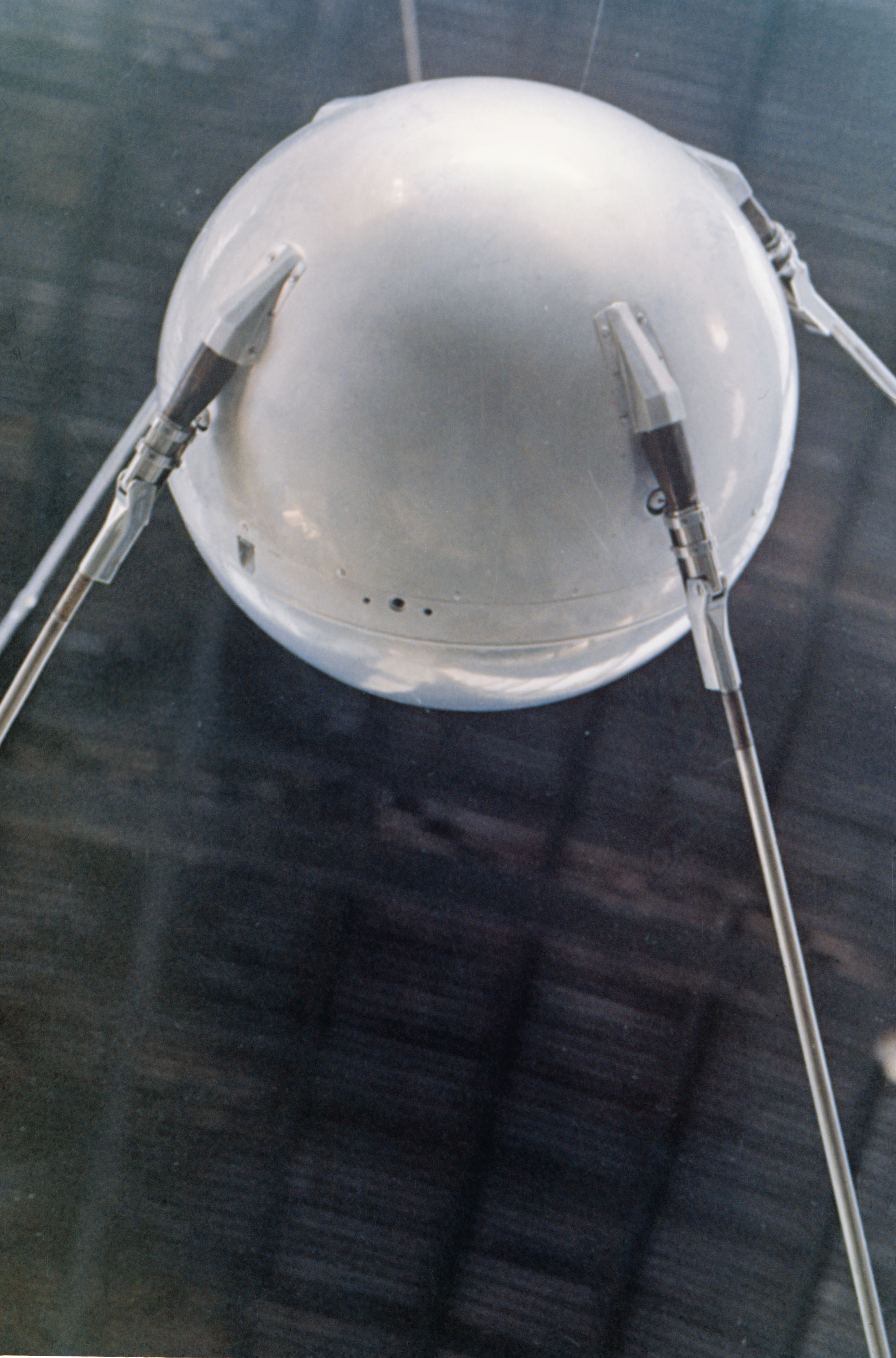 Sputnik 1 display model with a polished spherical body and long antenna rods.