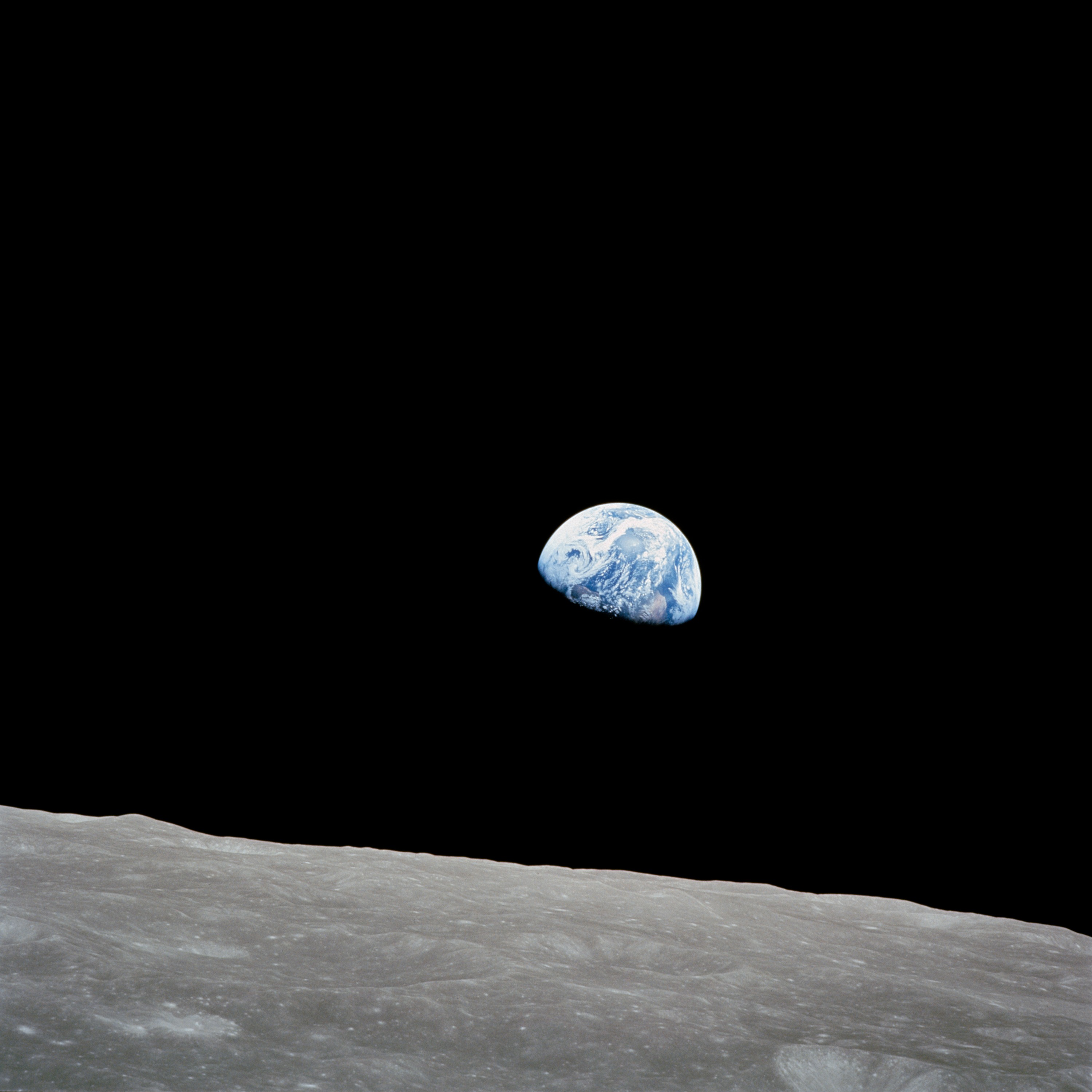 The blue-and-white Earth suspended in black space above the gray lunar horizon.