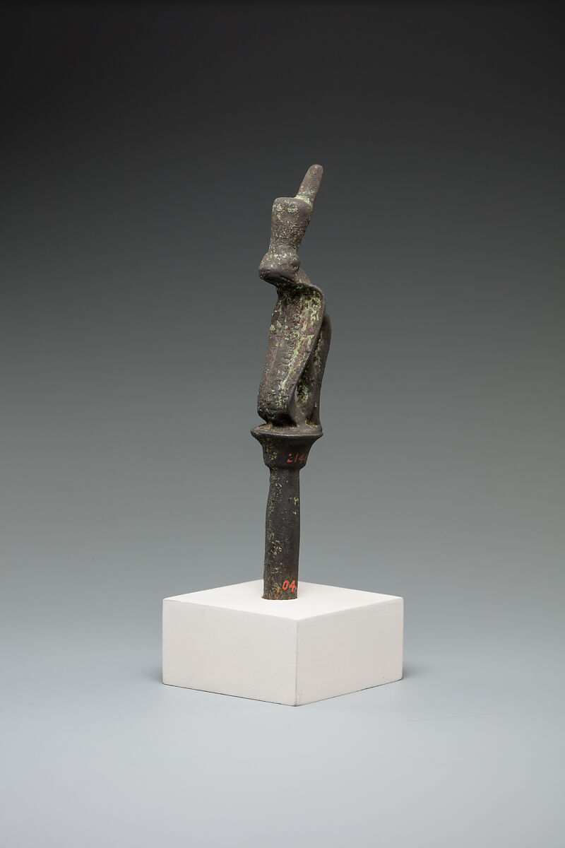 A small crowned cobra figure sits atop a slender plant-shaped stem on a modern museum display mount.