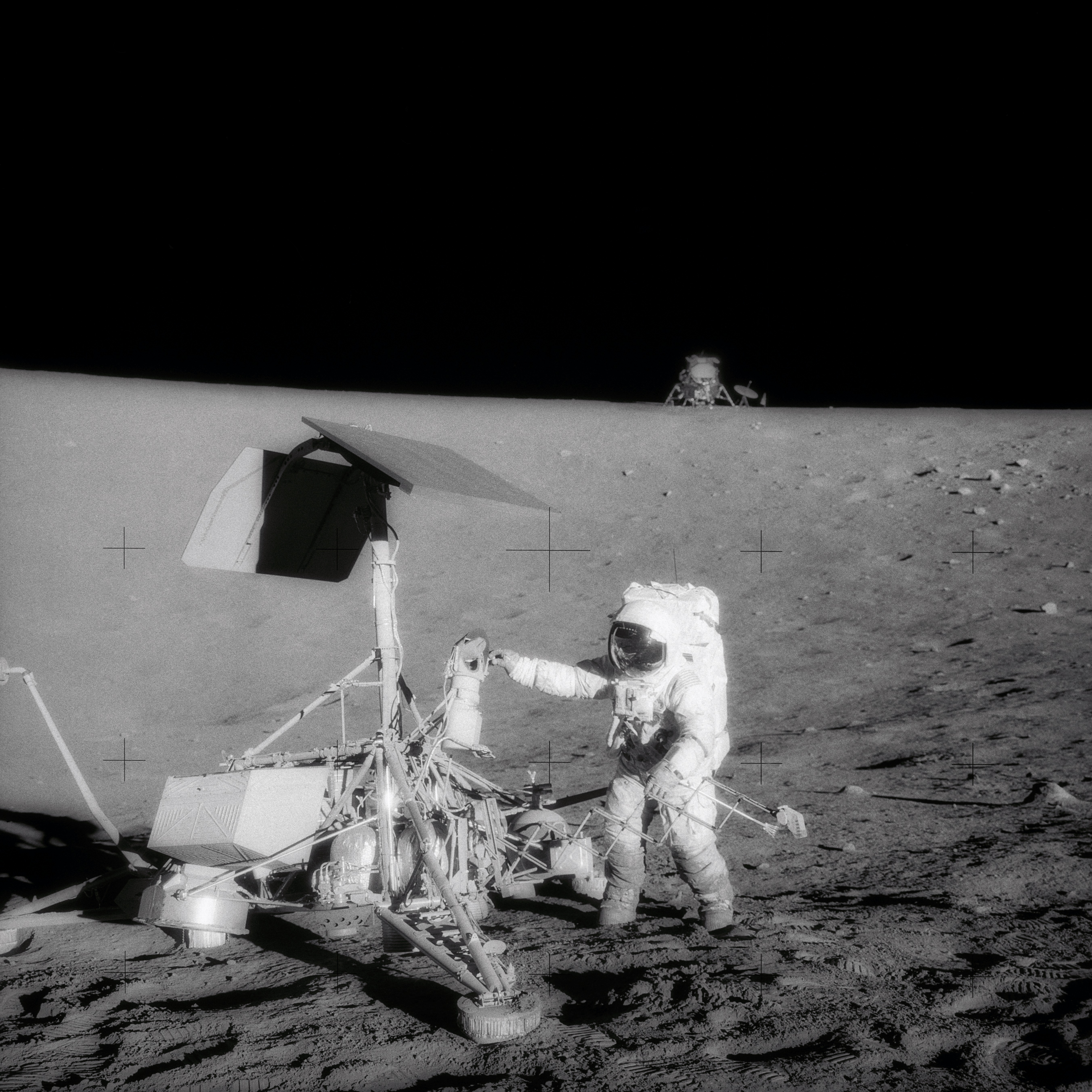 An astronaut beside the spindly Surveyor lander, with another spacecraft visible on the horizon.