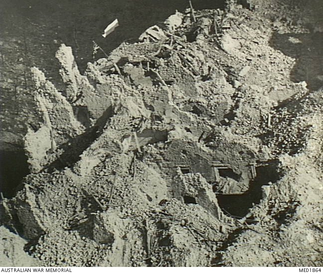 An aerial view of the ruined Monte Cassino monastery, with flags flying above the broken walls.